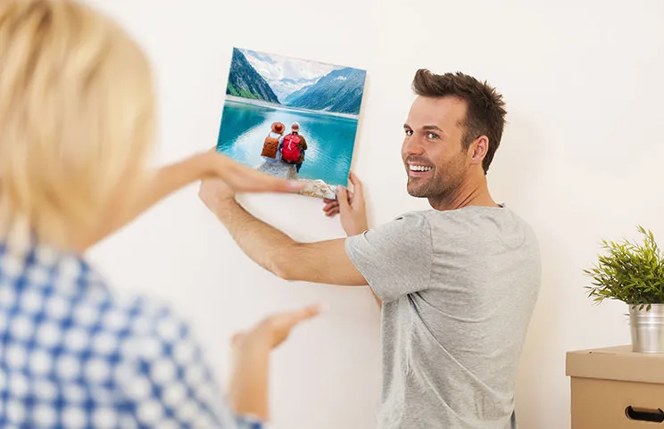 Man en vrouw die een fotocanvas ophangen met een vakantiefoto